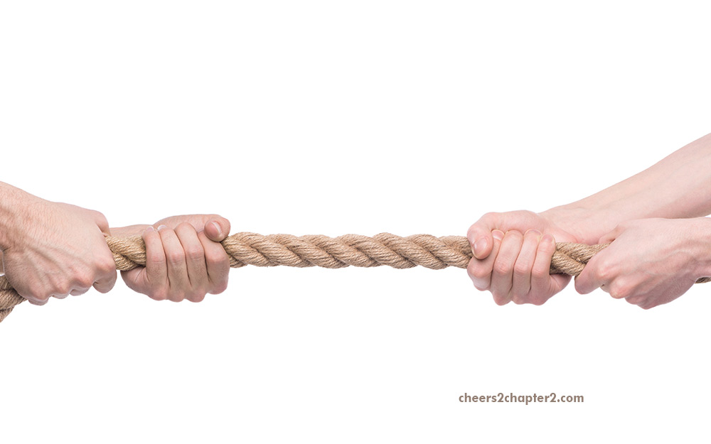 Two people in a power struggle tug of war with rope