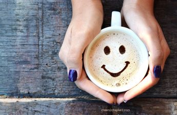 Image of woman's hands holding a cup of coffee with smile in it