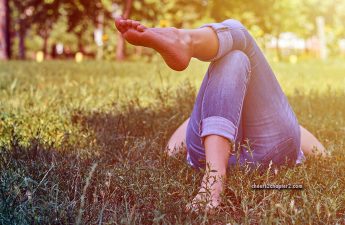 Woman lying in the grass barefoot for How to Get Yourself Grounded and How It Can Help You